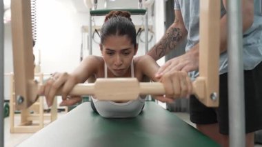 Pilates Cadillac masasında bar tabanlı bir alıştırmada bir müşteriye yardım eden eğitmen. Cadillac 'ta kuğu dalışı yapan kadın beden gücünü ve beden eğitimini arttırıyor. Alışkanlık.