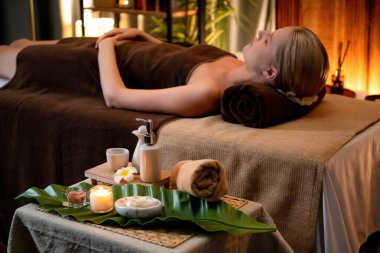 Aromaterapi masajı ambiyansı ya da spa salonu kompozisyon düzeneği bulanık kadınlara odaklı dekor mumları ve spa aksesuarları ile tatil köyü veya otel arka planında keyifli aroma spa masajı yapan. Sessiz.