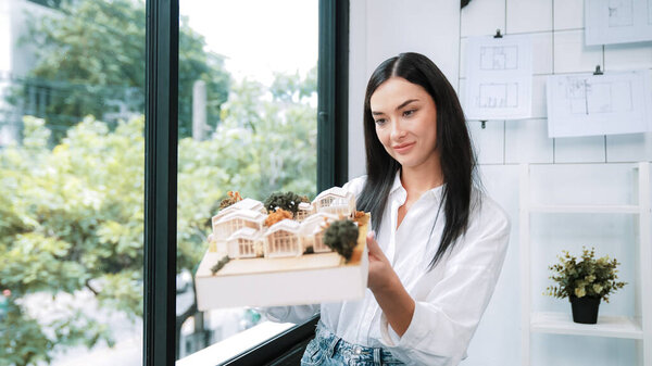 Крупный план квалифицированного молодого красивого кавказского архитектора лифта дом модели левой и правой стороны, чтобы проверить и сосредоточиться на проверке ошибок точки в современном офисе с чертежом. Непорочный.