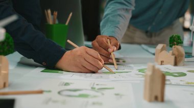 Çeşitli profesyonellerin elleri, yenilikçi çizimler ve modellerle dolu modern bir çalışma alanında sürdürülebilir çözümler arayarak işbirlikçi tasarım çalışmalarına giriştiler. SACTR