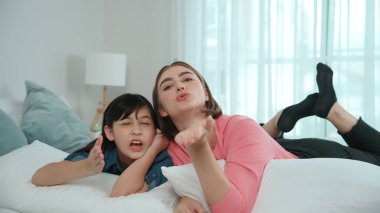 Mutlu Asyalı kız ve akıllı anne kameraya bakarken yatağa uzanıyorlar. Enerjik aile vakit geçirir ve birlikte yatmaya hazırlanır. Sevimli kız ve anne kameraya gülümsüyor sevgi ve şefkat gösteriyorlar. Pedagoji.