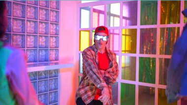 Kafkas dansçısı dans ederken çeşitli arkadaşları gece kulübünde neon ışıkta ayak seslerine bakıyor. Çoklu etnik kökenli hipsterin serbest stil müziğe geçişi ve mutlu bir adamın kameraya bakışıyla. Mutluluk.