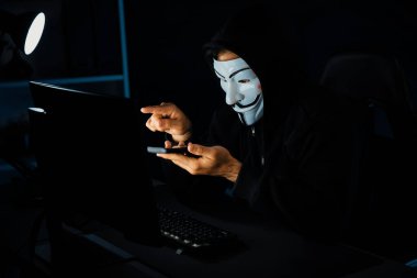 Beyaz gülümseyen isimsiz suçlu maskesi kurbana sesleniyor, kişisel bilgileri hacklemeye ikna ediyor, veri sunucu sistemindeki bilgisayar korsanlarının kullandığı şifreleme programını paylaşıyor. Tahmin et..