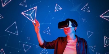 Heyecanlı, rahat gömlekli, mavi arka planda duran ve süzülen şekilli bir adam. Mutlu oyuncu metaevrene giriş yapıyor ve görsel gerçeklik dünyasına giriyor. Teknoloji yeniliği. Yaratıcılık.