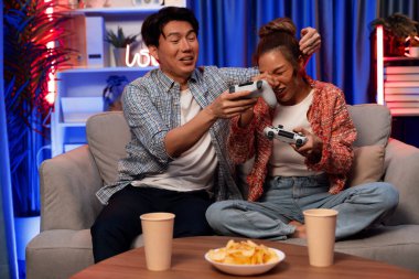 Oyun oynayan mutlu çiftin oturduğu kanepe joystickle oyun oynuyordu. Önden atıştırmalıklar ve kazanmak için gözlerini kapayan içkiler, evdeki modern neon ışıklı oturma odasında eğlenceli bir şekilde meydan okumaydı. İnfobahn.