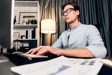 Akıllı iş adamı iş paragrafı dinamik pazarlama analizi planını analiz ediyor. Kağıt kağıtları ve bilgisayar monitörü raporlarını gece evdeki belge verileriyle karşılaştırmak için hazırlıyor. Bireysel.