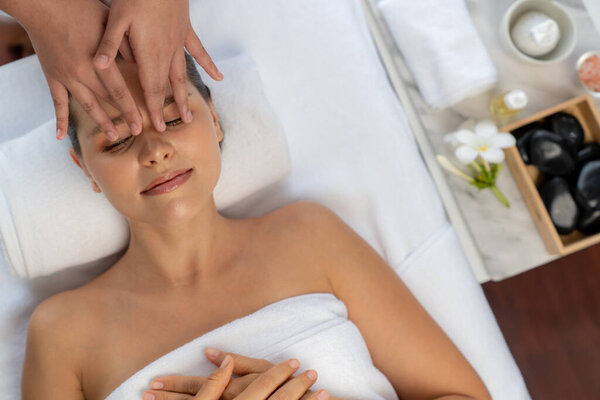 Panorama top view of woman enjoying relaxing anti-stress head massage and pampering facial beauty skin recreation leisure in dayspa modern light ambient at luxury resort or hotel spa salon. Quiescent