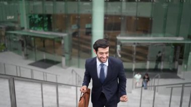 Terfi alma, satışları artırma, maaşları artırma konusunda iyi haberleri kutlamak için dans eden mutlu iş adamı şehirde geçmişi bulanık bir şekilde merdivenlerden çıkarken. Neşeli bir ruh hali. Sevinçli..