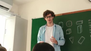 Zeki öğretmen sınıfta fikri açıklarken matematik teorisine işaret ediyor. Profesyonel eğitmen, öğrenciye bakıp matematik dersinde tahtaya basarak fikir hakkında konuşuyor. Pedagoji.