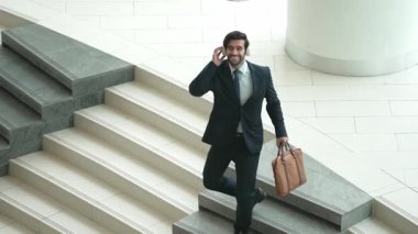 Merdivenlerden inerken kulaklıktan müzik dinleyen mutlu bir iş adamı. Yönetici, satışların artmasını, başarılı projeleri veya yeni pozisyonları kutlamak için dans ediyor. Sevinçli..