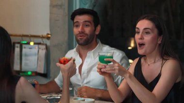 Birkaç arkadaş renkli karışık kokteyller içerken garsonlar da yemek masasında özel bir partiyi kutlamak için yemek ve içecekler lezzetlidir. Vinosity.