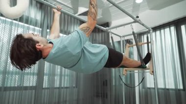 Çekirdek dayanıklılığı ve spor salonunda vücut egzersizi için pilates trapez masasına tırmanan bir adam. Eğitmen, arka ve kalça esnekliğini arttırmak için Cadillac 'ta ters asılı duruyor. Alışkanlık.