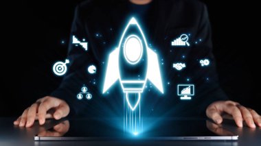 Modern bir iş adamı dizüstü bilgisayarla etkileşime girerken, bir roket ikonu yenilikçi büyüme stratejilerini sembolize ediyor, hırsı ve dijital ortamdaki ilerlemeyi yansıtıyor. Dörtgen