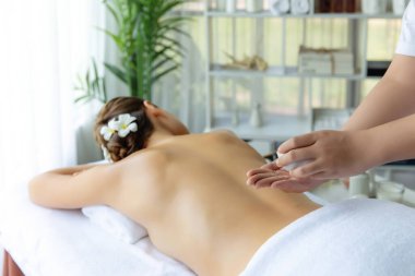 Masör elleri kadının sırtına aroma yağı döküyor. Masözler lüks otellerdeki kaplıca salonundaki müşteriler için yağ masajı prosedürü hazırlıyorlar. Aroma yağı vücut masajı konsepti. Sessiz.