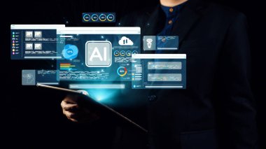 Bir işadamı, çeşitli yapay zeka arayüzleri ve grafikleri iş dünyası üzerindeki teknolojik etkisinin altını çizerek karanlık bir ortamda ortaya çıktığı bir tableti güvenle tutuyor. Dörtgen