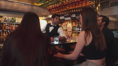 Lüks bir barda VIP müşterisi olan zeki bir barmen sıcak bir gece kulübünün ışıklandırma atmosferinde canlı bir sohbet için tezgahta yeni ve güzel bir konuğu selamlıyor. Vinosity.