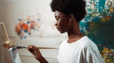 Afrikalı erkek tuvali sıcak tonda boyarken, beyaz elbiseli kız renkli duvarın arkasında havalı renkler çiziyor. Yaratıcı aktivite konsepti. Öğretim.