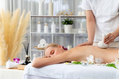 Sıcak bitkisel top spa masaj vücut tedavisi, masör kadın vücuduna nazikçe şifalı bitki torbası bastırıyor. Aromaterapi dinlenme sükuneti ve sükuneti kaplıca salonundaki atmosferi aydınlatıyor. Sessiz.