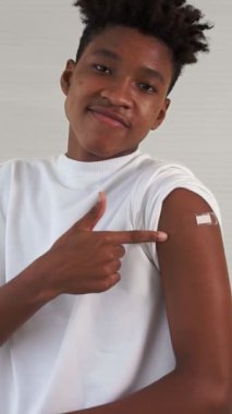 Afrikalı Amerikalı genç COVID-19 aşısı gösteriyor. Koronavirüs aşısı konseptiyle neşeyle sargılanıyor. Vatandaşı aşılamak için. .