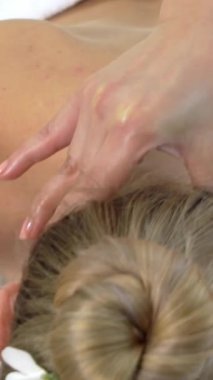 Lüks bir spa merkezinde masaj terapisti tarafından boyun ve kafa masajı için spa 'ya uzanan rahat bir kadın. Sağlık, stres atma ve gençleştirme kavramı.