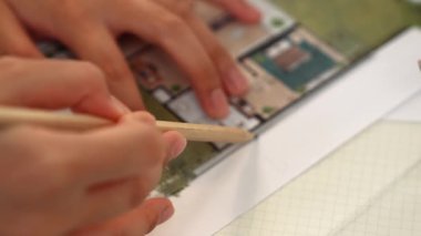 Mimari ekipmanlarla toplantı masasında ev tasarımı üzerine profesyonel mühendis ekibi tartışması ve modern ofiste bina planı dağılımı. Eline odaklan. - Yakın çekim. Tanımlama.