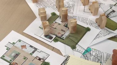 Mimar ve mühendis, mimari belge, ölçüm aracı ve ahşap bloğu ofis çevresinde dağıtan planlar kullanarak inşaat inşaatı hakkında düşünür veya tartışır. Tanımlama.