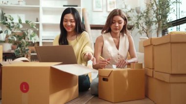 Çekici bir oda arkadaşı oturma odasında paket paketlerken pakette konum yazıyor. Mutlu satıcı birlikte çalışıyor ve teslimat paketini hazırlıyor. Girişimci kargo kutusu paketliyor. Myrmidon.