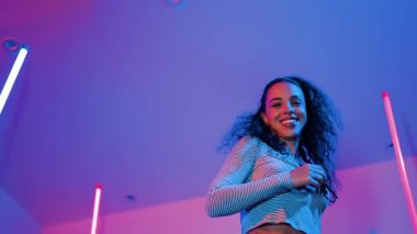 Latin dansçıların kameraya bakıp şehrin pop müziğiyle dans ettiği düşük açılı kamera. Profesyonel çekici hipster, mor veya neon ışıklı hip hop şarkısına geçiyor. Şık bir kumaş. Mutluluk.