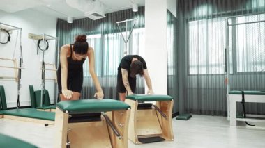 Müşteriler pilates antrenmanı sırasında ayakta gerinme egzersizi yapıyorlar. Esnekliği artırmak için. Spor salonunda bacak dayanıklılığı. Çekici grup esniyor ve eğiliyor. Alışkanlık.
