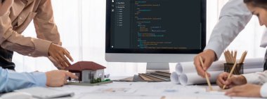 İç mimar tasarımcı grubu, daha kesin tasarım için planlar ve dizüstü bilgisayar ekran mimari yazılımı üzerinde birlikte tartışıyorlar. Modern ev tasarımı ve yenileme. İçgörü