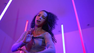 Latin dansçıların kameraya bakıp şehrin pop müziğiyle dans ettiği düşük açılı kamera. Profesyonel çekici hipster, mor veya neon ışıklı hip hop şarkısına geçiyor. Şık bir kumaş. Mutluluk.