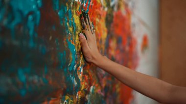 Renkli duvara yerleştirilmiş liseli kız elinin yan görüntüsü ve elini çek. Resim dersinde odanın kapatılması ya acı verici ya da el iziyle süslenmişti. Yaratıcı aktivite konsepti. Öğretim.