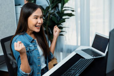 Mutlu yüzlü gülümseyen Asyalı genç bilişim geliştiricisi bilgisayar ekranlarına bakarak yeni yazılım geliştirme bilgi projesi alıyor, merkez ofiste test etmek için program kodlaması yaratıyor. Taktik.