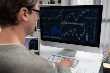 Bilgisayar ve dizüstü bilgisayarı kullanarak, çalışma masasındaki dinamik artırılmış borsa grafiğinin en yüksek kar değerini araştıran bir tüccar, modern ofisteki ekrandaki döviz kuru değerini analiz ediyor. Bireysel.