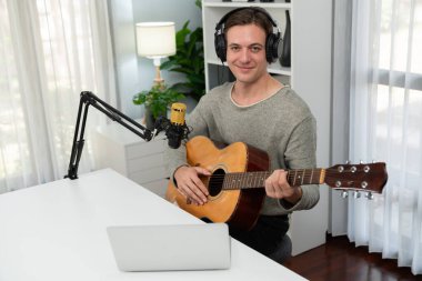 Akıllı şarkıcı görünümlü kamerada sunucu kanalı, şarkı söylerken gitar çalmak, sosyal medya kanalında yayın yapmak, modern stüdyo kaydında video kaydedici olarak kulaklık takmak. Bireysel.