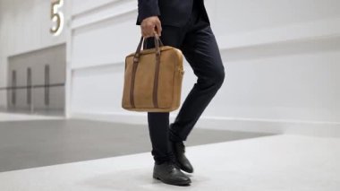 Profesyonel iş adamının bacağını tutarken yakın plan fotoğrafı. Proje yöneticisinin bacağa odaklanmış görüntüsü. Seyahat, taşınma, yolculuk, yürüyüş, yeni bir pozisyon alma, iş değiştirme. Sevinçli..