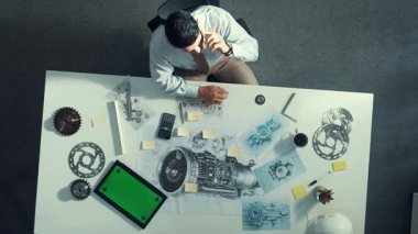 Türbin motoru veya jet motoru tasarımı ve çeşitli metal teçhizat dağılımı ile toplantı masasında yeşil ekranlı tablet üzerinde çalışırken telefona bakan mühendis görüntüsü. Hizalama.