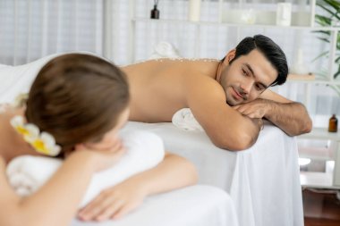 Lüks spa salonlarında sıcak mum ışığında cilt bakımı gören mutlu çift müşterisi. Sağlık kaplıcasında güzellik tedavisiyle tuz temizliği. Sessiz.