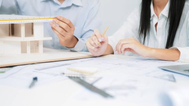 Profesyonel mühendis ev modelini tartartarken, yetenekli tasarımcı da planına yazar. Birlikte çalışmak, işbirliği, işbirliği. Yaratıcı tasarım ve takım çalışması konsepti. - Yakın çekim. Tertemiz.