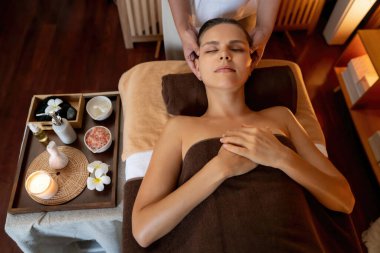 Beyaz kadın stres önleyici kafa masajı yapmaktan ve lüks otel veya otelde sıcak mum ışığında yüz güzelliği eğlencesi yapmaktan zevk alıyor. Sessiz.