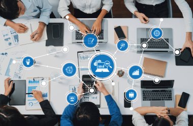 Dinamik bir iş ekibi, etkili karar verme ve stratejik planlama için teknoloji ve veri analiz araçları kullanan modern bir ofis ortamında işbirliği yapmaktadır. Dostluk