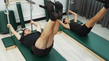 Bir grup müşteri, çekirdek dayanıklılığını ve bacak bağını geliştirmek için Cadillac reformatör makinesinde pilates egzersizleri yapıyor. Sağlıklı müşterilerin daha düşük poz verip kaldırma pozlarının üst görüntüsü. Sağlıklılık. Alışkanlık.