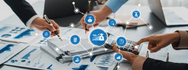 Profesyonel bir ekip, vergi ve ekonomik verileri canlı bir ofis ortamında değerlendirmek için hesap makineleri ve belgeler kullanarak mali analiz üzerinde işbirliği yapar. Dostluk