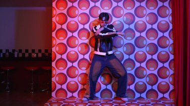 Asyalı break dansçı serbest stile geçiyor ve balon arka planlı kameraya bakıyor. Profesyonel hippi gündelik kıyafet giyer ve gözlük takar. Mutluluk.