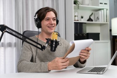 Akıllı yayıncının sunucu kanalı canlı sosyal medya yayını ile dinleyicilere senaryo okuyarak, kulaklık takarak modern ev stüdyosundaki video flamalarını kaydediyor. Bireysel.