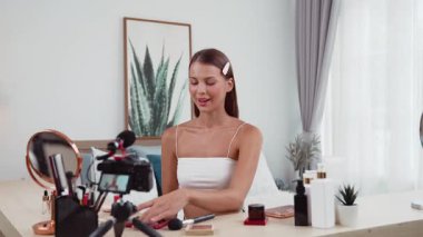 Genç kadın canlı yayına başlıyor. Sosyal medya için güzellik ve kozmetik video içeriği. Güzellik blogcusu kameraya gülümserken seyircilere ve takipçilere güzellik bakımını gösteriyor. Düzenle