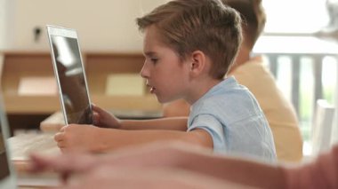 Bilgisayar üzerinde çalışan beyaz çocuğun yan görüntüsü. Mühendislik ödevi sırasında. Çekici çocuklar bilgisayar yazılımı kullanarak yapay zeka ya da programlama sistemini öğreniyor ya da öğreniyor. Pedagoji.