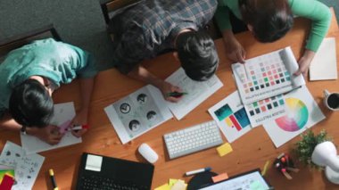 Takım ayakta dikilirken ve yorum yaparken müdürün fikir yazma konusunda üst düzey görüşü. Profesyonel tasarımcı logosu renk paletine bakarken ve renkli kalemle fikri kağıda yazarken. Sempozyum.