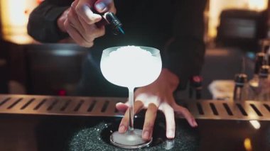 Yakın plan votka kokteyli ve Asyalı barmen gece kulübündeki lüks tezgahta şeker sunumuna ateş yakıyor. Gece hayatı karışımının sergilendiği özel bir içecek sıcak ışığı davet ediyor. Vinosity.