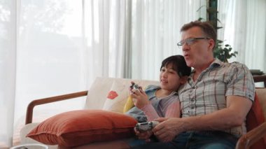Granddaughter teaching grandfather play console game, entertainment hobby. Old senior use technology communicate with new generation kid cross generation gap strengthen family bond. Divergence.